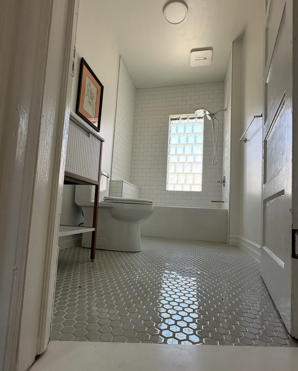 Bathroom with white subway tile around a bathtub, a glass-block window, and a hexagon tile floor.