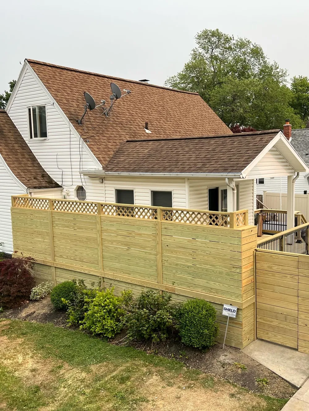 Wooden privacy screen around a deck, with horizontal boards and lattice along the upper edge.